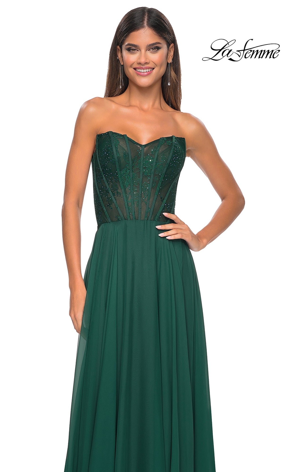 A woman stands gracefully in the La Femme Lace-Bodice Long A-Line Prom Dress 32311, her elegant green gown flowing beautifully for the occasion.
